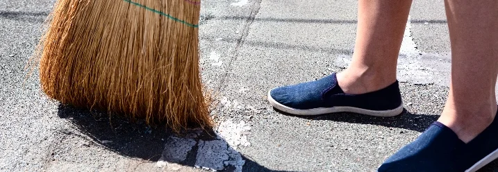 Person fegt Boden mit Besen